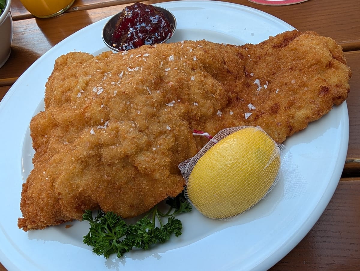Ein großes Wiener Schnitzel mit Zitrone, Petersilie und Preiselbeeren