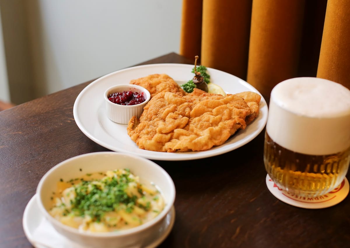 Wiener Schnitzel mit Preiselbeeren, dazu eine Schüssel Erdäpfelsalat und ein Krügerl Bier